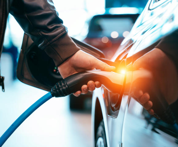 man connecting charger cable to electric vehical