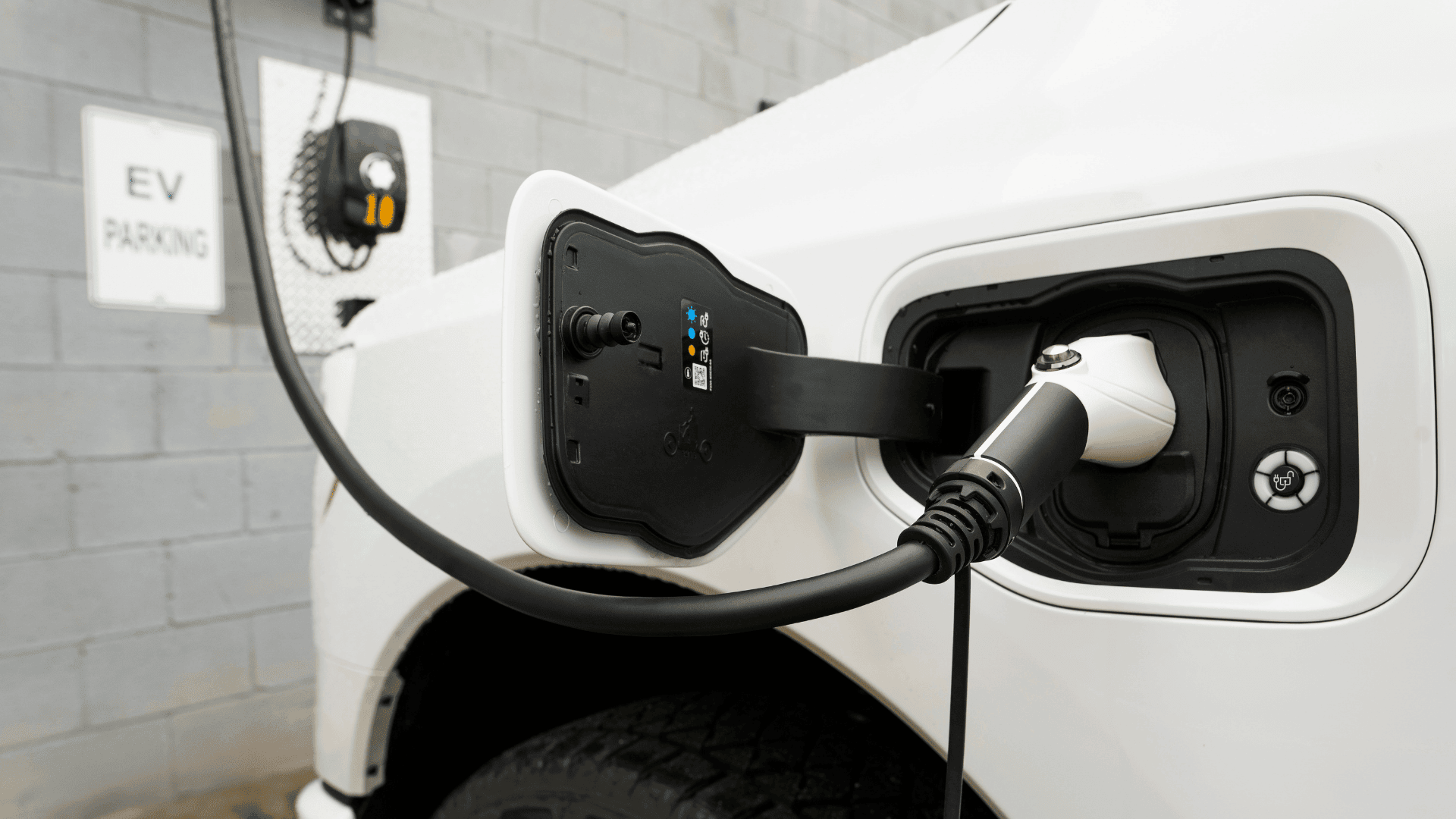 Close-up of an electric vehicle being charged at a charging station in an EV parking bay.