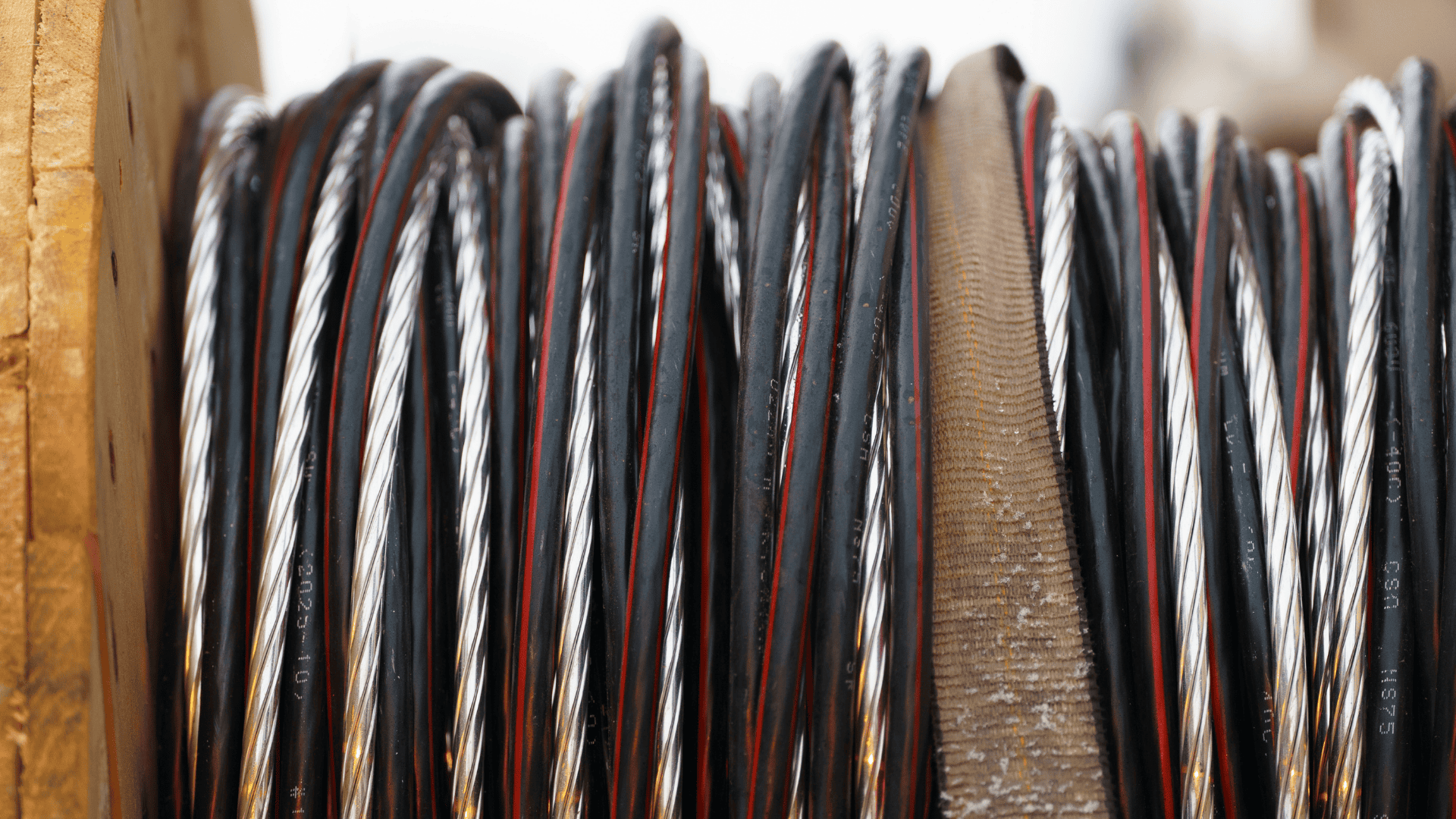 Close-up of industrial metal cables wound around a large wooden drum.